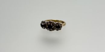 An 18ct gold three-stone graduated sapphire ring within a white metal mount set twenty diamond point