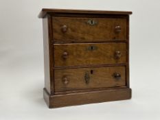A late 19th Century miniature walnut table chest with fitted three long drawers on plinth base