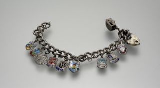 A silver kerb link chain bracelet with heart shaped padlock and eight silver Scottish and European