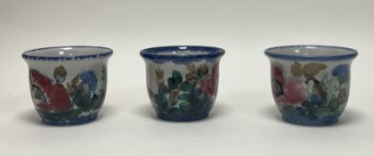 A collection of three Highland Stoneware plant pots each decorated with poppies and thistles on a
