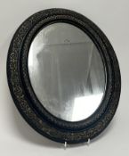 A 20thC oval gilt and ebonised mirror decorated with scrollwork and foliate detail (l. 46cm)