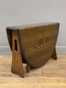 A modern elm drop-leaf side table by Ercol, oval top with drop-leaves on gate-leg mechanism to sides