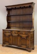 A reproduction oak kitchen dresser, moulded cornice over shaped apron, three plate racks on a base