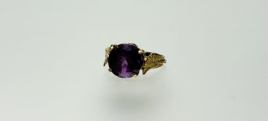 An Egyptian yellow metal ring set circualr round facet cut amethyst coloured stone approximately 3.