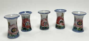 A collection of five Highland Stoneware vases of trumpet-form, each decorated with red poppies and