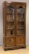 A late 19th/ early 20th century oak Arts and Crafts bookcase, with twin arched glazed doors to front