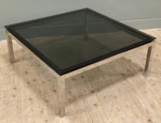 A modern chrome-finish and glass coffee table, with square smoked glass top raised on square