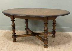 A modern extendable elm Ercol dining table, oval top with internal fold-out leaf, raised on shaped