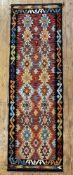 A hand-knotted Chobi kilim runner, repeating geometric motifs to centre on a soft red ground: L.
