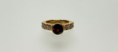 A modern 9ct gold ring set circular red facet cut stone three white metal set diamond points M/N 7.