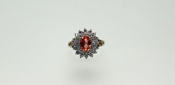 A modern 9ct gold cluster ring set oval facet cut coloured stone within a double halo of clear
