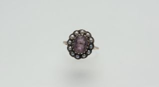 A 9ct gold ring set oval facet cut amethyst - chip to side and table within a surround of half