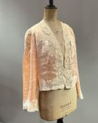 A 1920s F. Duvelleroy silk satin blush bed jacket with applied lace detailing and wool lining to