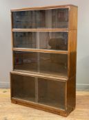A mid-century oak sectional bookcase, fitted with four sections each with sliding glazed doors to