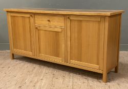 A modern oak sideboard, rectangular top over central drawer and cupboard door, flanked by twin