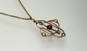 An Edwardian 9ct gold oval openwork pendant set with a central garnet coloured facet cut stone