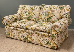 A country house two-seater sofa, upholstered in cream chinz fabric with yellow and green flowers,