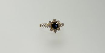 A modern 9ct gold ring set blue circular facet cut stone within a halo surround of clear stones