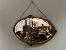 An Edwardian oval walnut mirror with carved stained wooden scrolling detail to edges (a/f to one) (