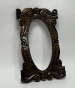 An early 20th Century carved mahogany mirror frame/picture frame, with central oval space and carved