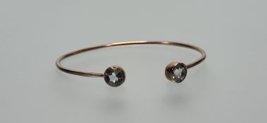 A 9ct rose gold open bangle with inset faceted stone terminals: d. x 7cm 10.8g