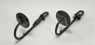 A pair of wrought iron wall-mounted candle sconces in the form of fish hooks, with knot detail to