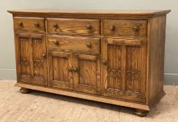 An Ercol Canterbury ash and elm dresser base, fitted with four drawers to front over four tracery
