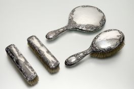An Edwardian Chester and Sheffield silver backed four piece dressing table brush set with chased