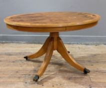 A reproduction yew and walnut coffee table, cross-banded oval top raised on splayed supports with