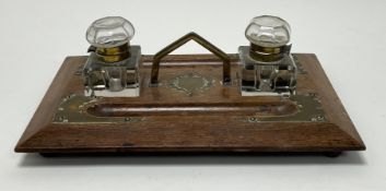 An Edwardian oak and brass-mounted desktop inkwell, raised on four bun feet (l. 31cm x w. 23cm)