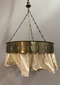 An Edwardian brass ceiling lamp, pressed brass band with cream fabric, suspended from chain and