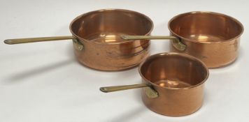 A graduated set of three British copper pans with brass handles (d. largest 19cm) (3)