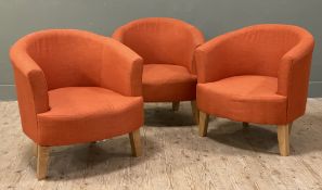 A set of three modern tub chairs, upholstered in orange fabric and raised on splayed square