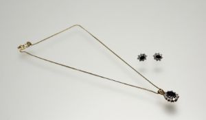 A 9ct gold pendant set oval blue stone within a surround of twelve facet cut clear stones: