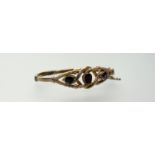 An Edwardian yellow metal stiff-hinged bracelet set three garnets a/f: d. x 6cm 11.3g