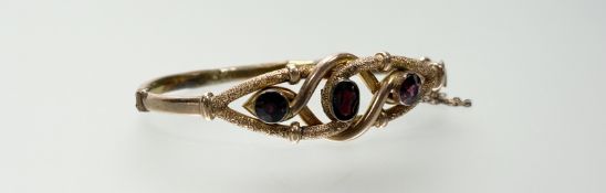 An Edwardian yellow metal stiff-hinged bracelet set three garnets a/f: d. x 6cm 11.3g