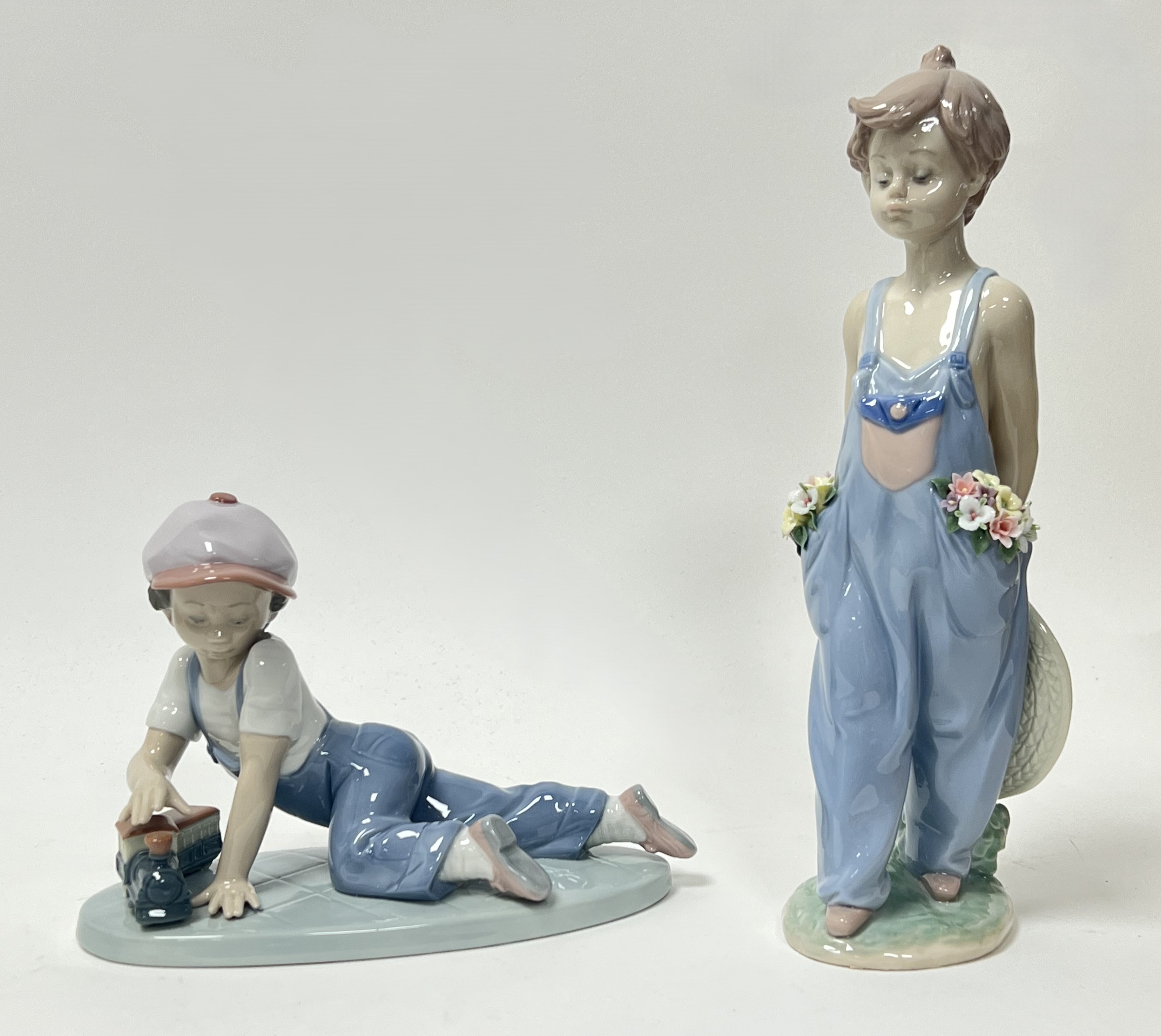 A Lladro porcelain figurine 'All Aboard', modelled as a young boy playing with a train set, No.
