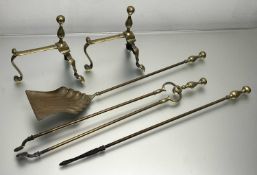 An Art Nouveau brass fireside companion set comprising a pair of fire dogs with scroll feet, a