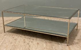 A modern two-tier glass coffee table, inset glass top raised on patined metal supports over a low-