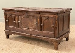 A late 17th/ early 18th century oak coffer chest on stand, plank top with three-panel carved