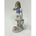 A Lladro porcelain figure of 'Dropping The Flowers', modelled as a young girl standing above flowers