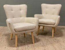 A pair of modern armchairs, cream upholstery with tufted back and seat raised on tapered turned