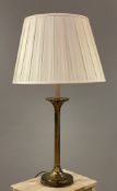 A modern brass table lamp, faux-candle top on column supports and circular base, with pleated