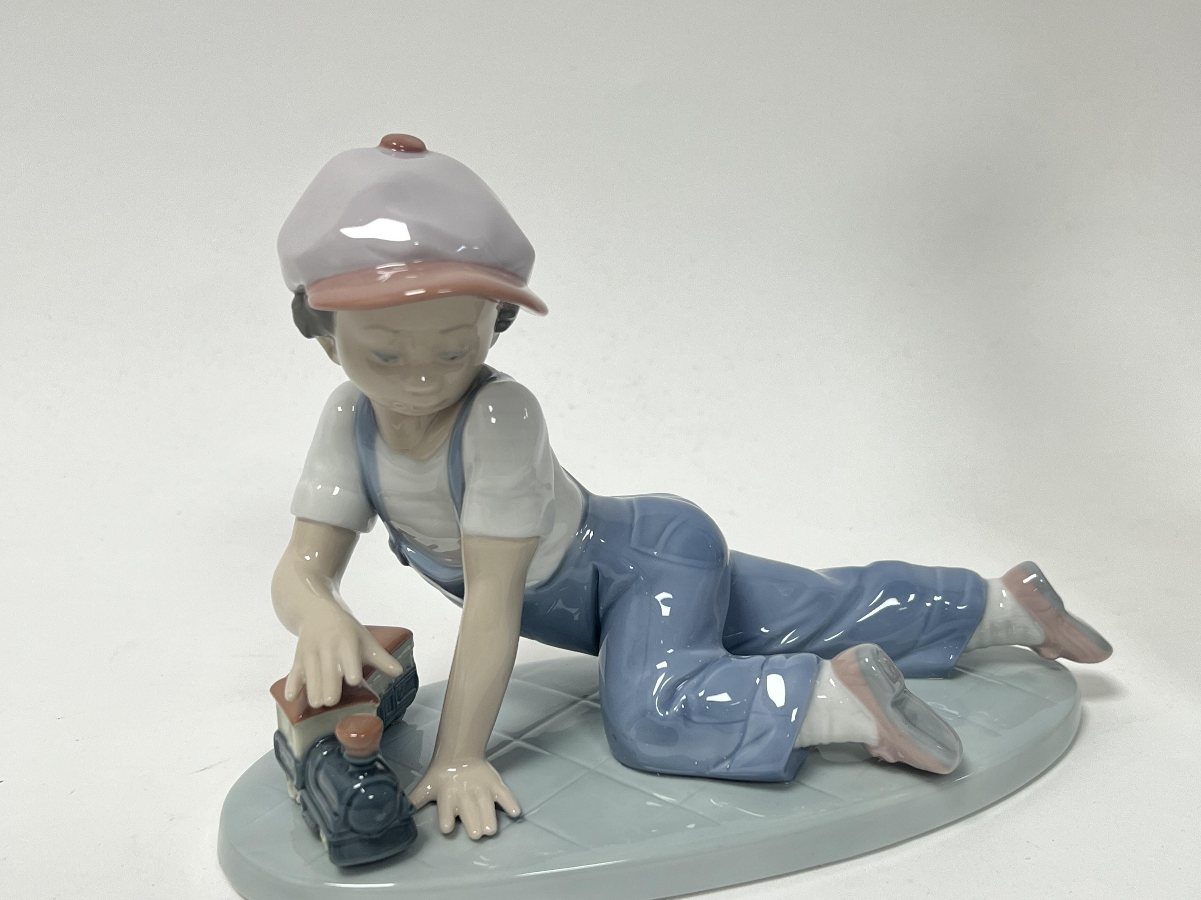 A Lladro porcelain figurine 'All Aboard', modelled as a young boy playing with a train set, No. - Image 2 of 6