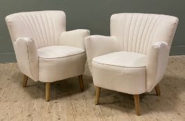 A pair of modern armchairs, cream upholstery with piping detail to backs, raised on turned