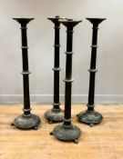 A set of four 19thc black painted pine floor standing altar candlesticks with ringed tapered columns