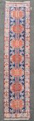 A hand-knotted Caucasian Kazak runner, dark indigo field with seven geometric medallions, enclosed