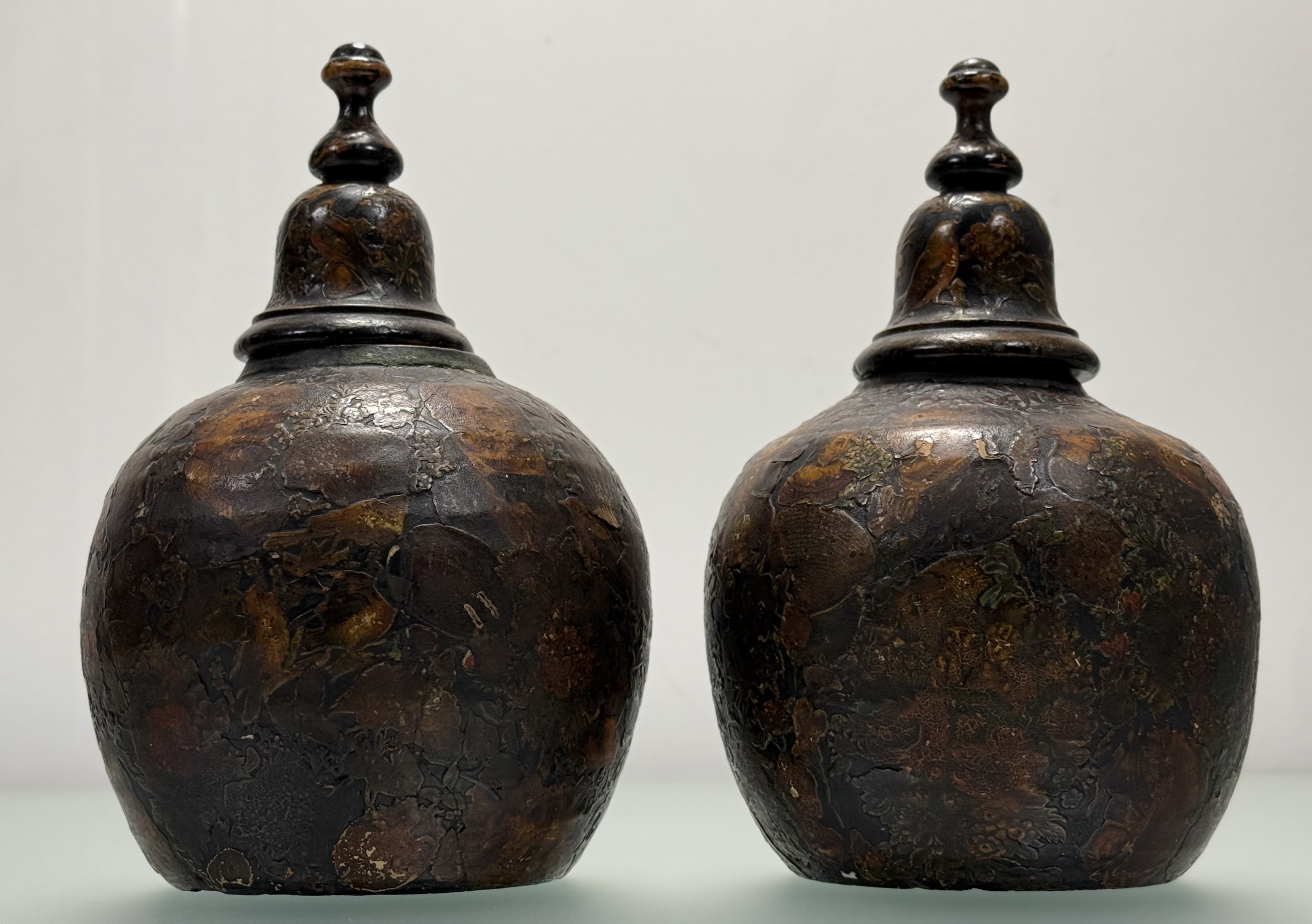 A pair of 19th century decoupage pottery urns, applied with figures and flowers, and with domed