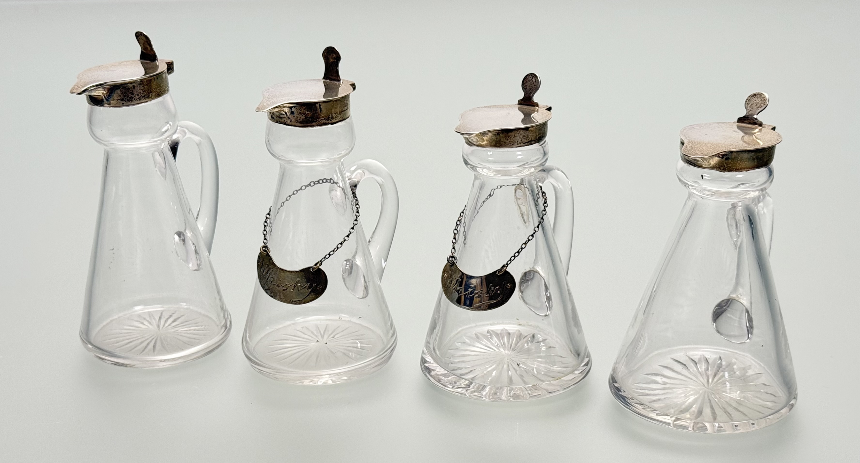 An assembled set of four silver-mounted cut-glass toddy jugs, two Hukin & Heath, Birmingham 1931,