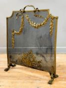 An Edwardian brass firescreen, the mesh screen applied with foliate and floral swags and raised on